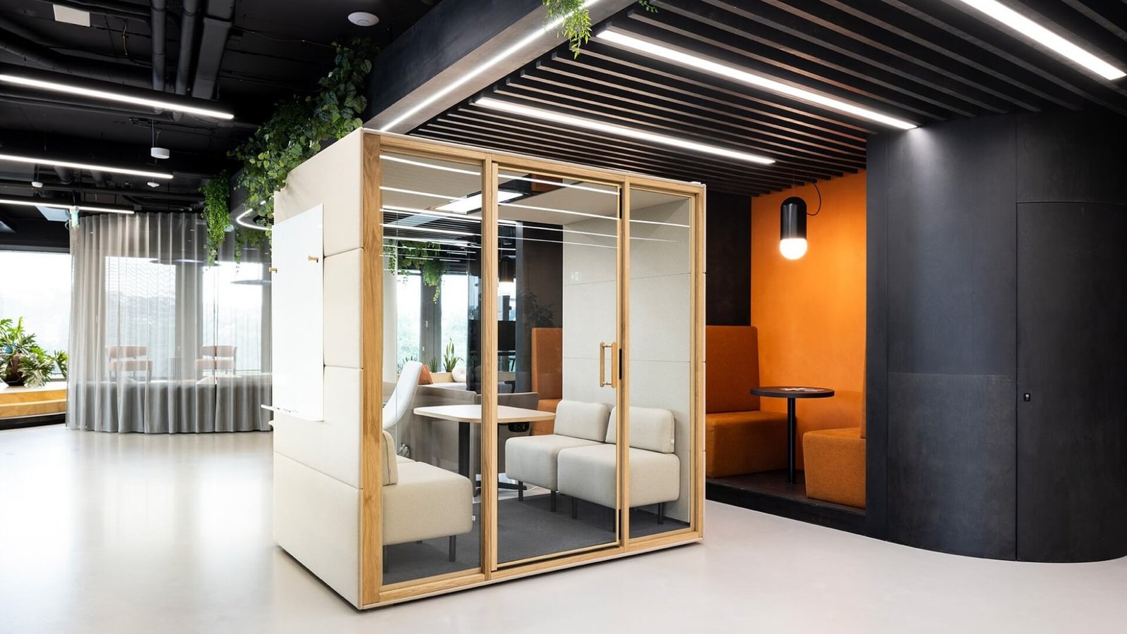 Interior de una oficina moderna con cabina acústica Chat4 GEN4, zonas de descanso y plantas decorativas