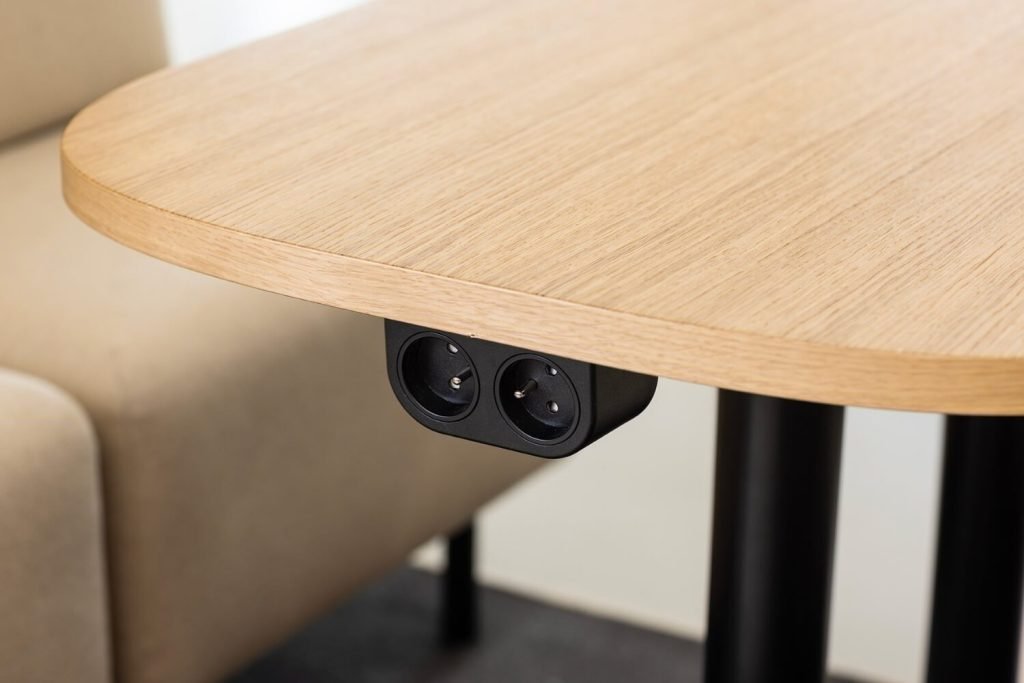 Mesa de trabajo de madera con dos tomas de corriente integradas bajo el tablero. Detalles del interior de una cabina acústica Chat4 GEN4