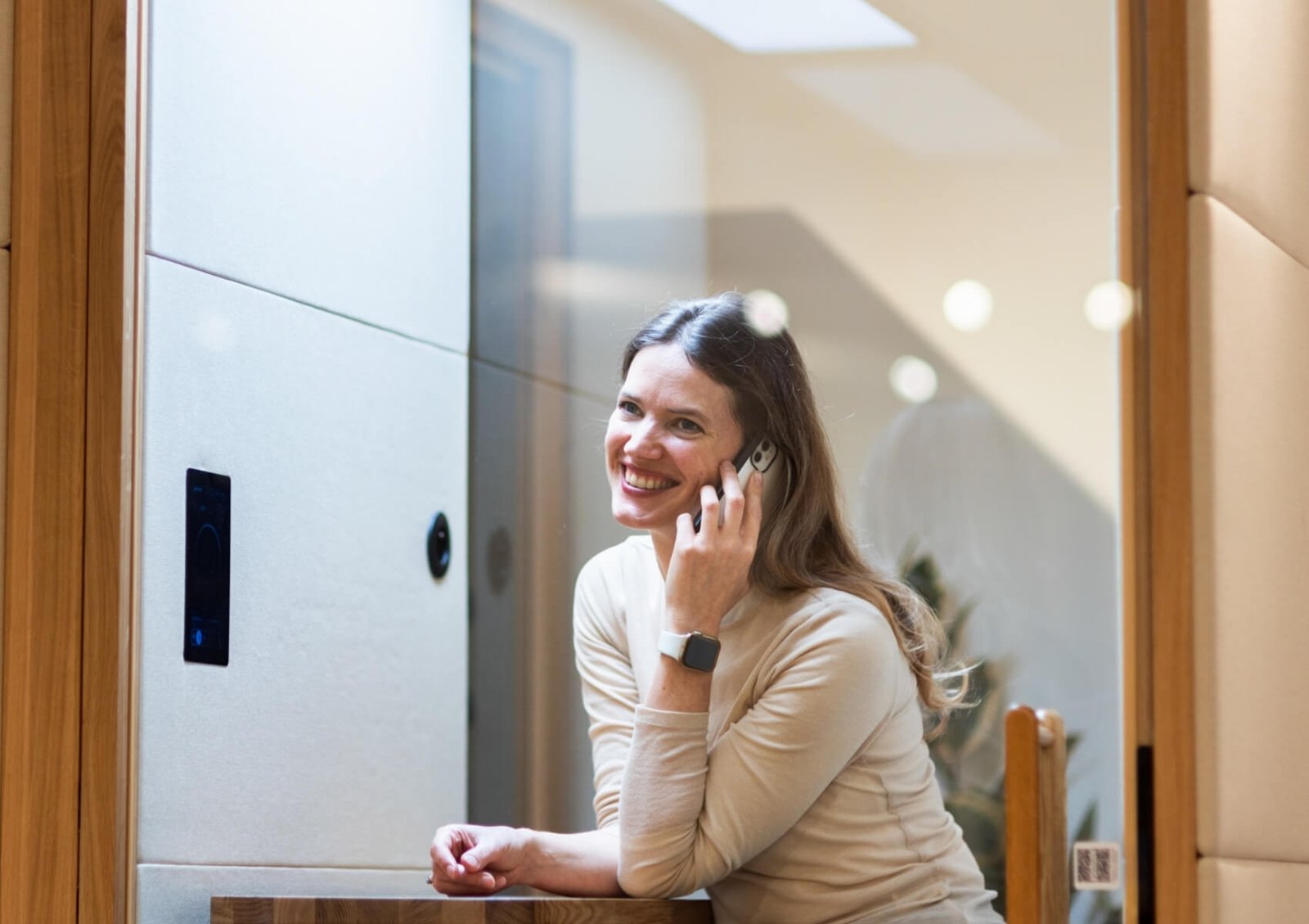 Mujer sonriente hablando por teléfono dentro de una cabina acústica Spot GEN4