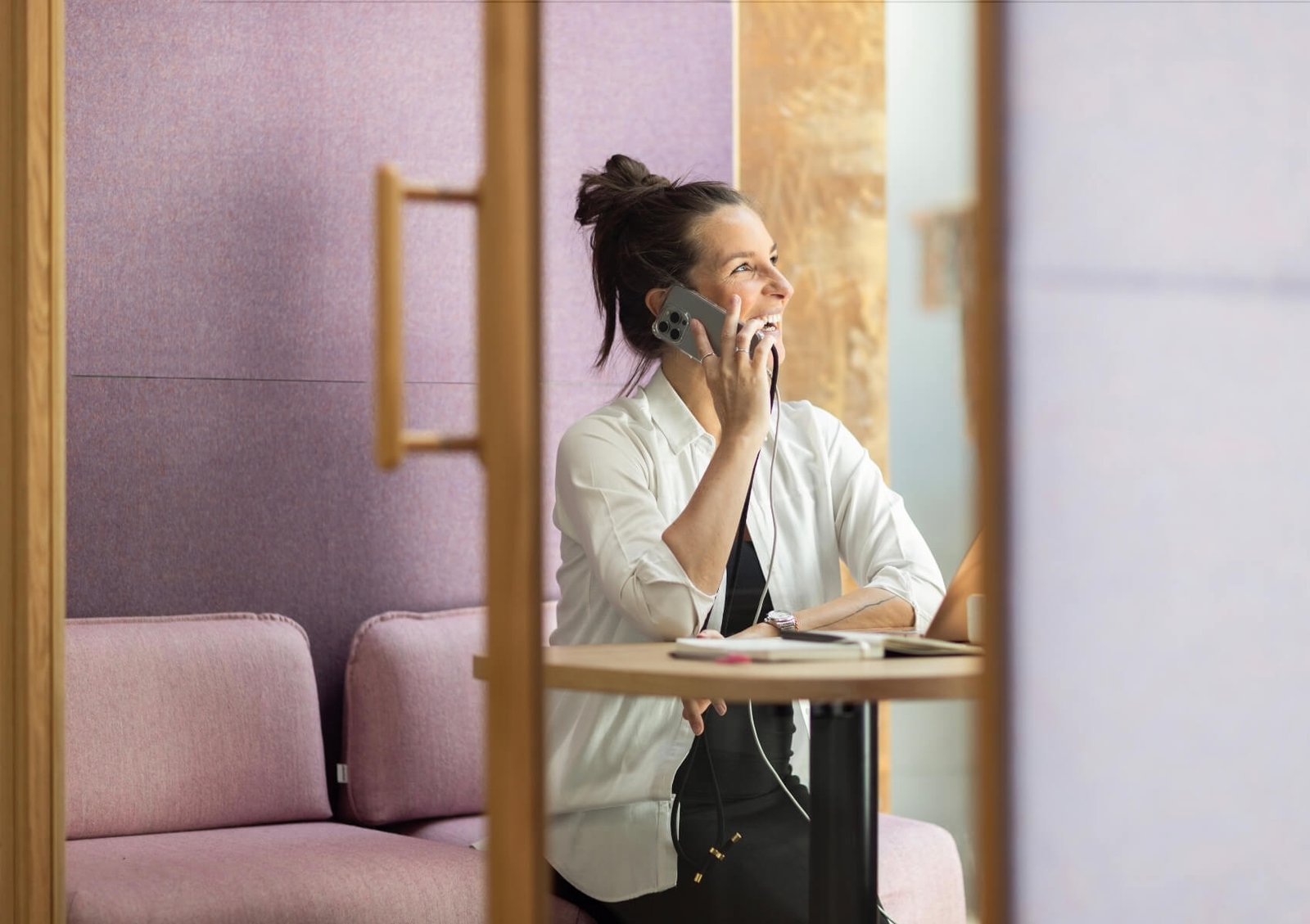Mujer sentada en un espacio de trabajo mientras habla por teléfono móvil dentro de una cabina acústica Chat4 GEN4