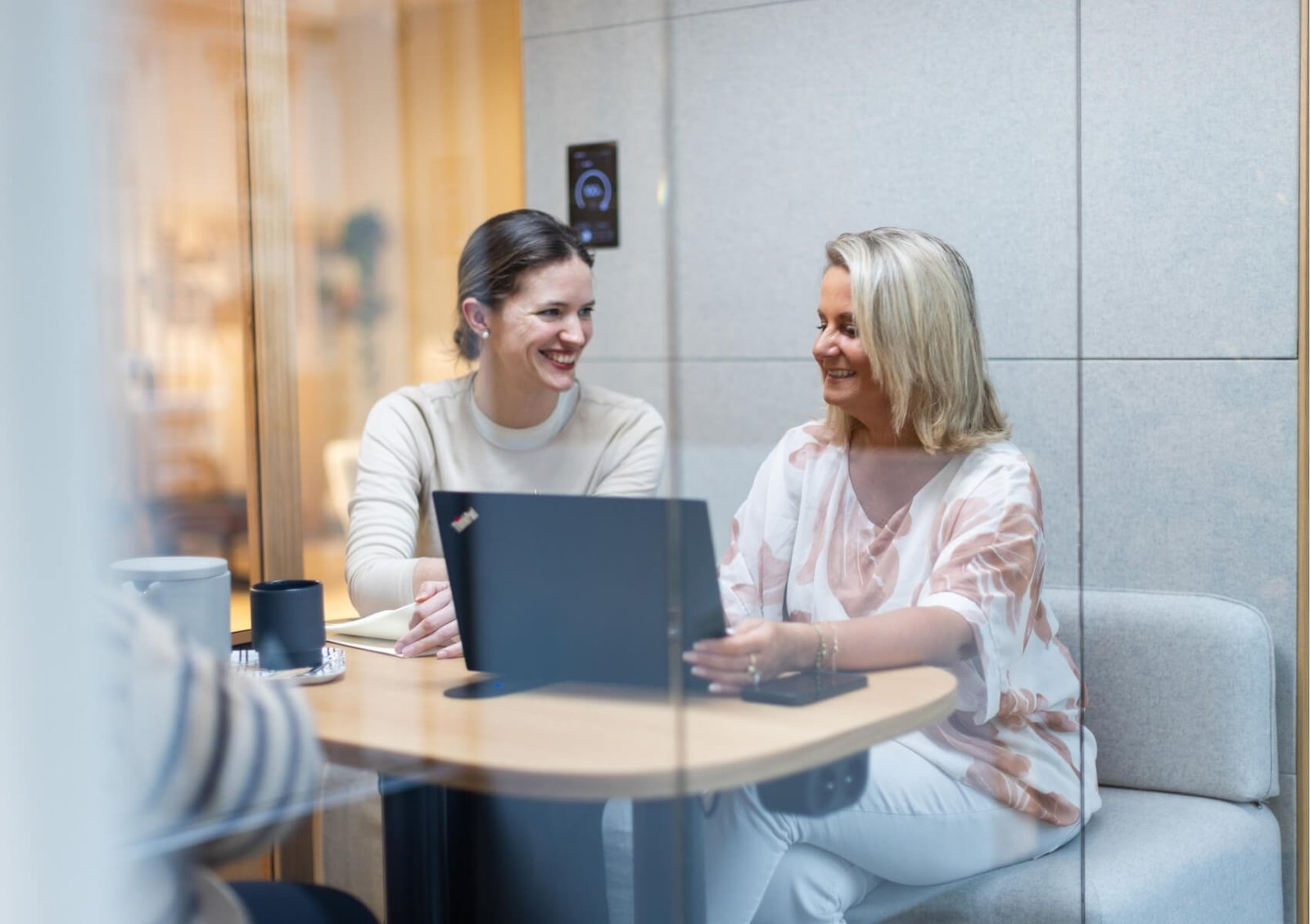 Dos mujeres conversan en una mesa con un portátil en una cabina acústica Chat4 GEN4