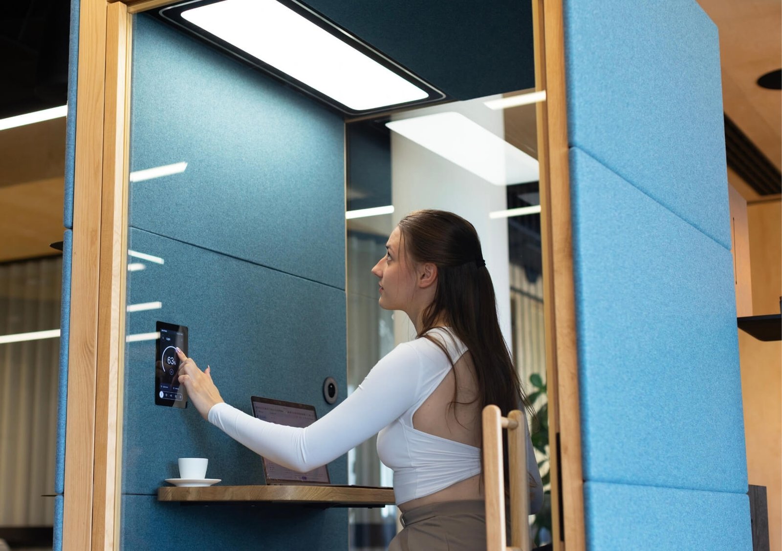 Una mujer ajusta un panel de control en una cabina de trabajo insonorizada Spot GEN4