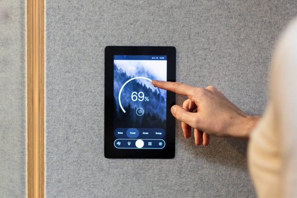 Una mano toca una pantalla mural que muestra un nivel de sonido del 69 %