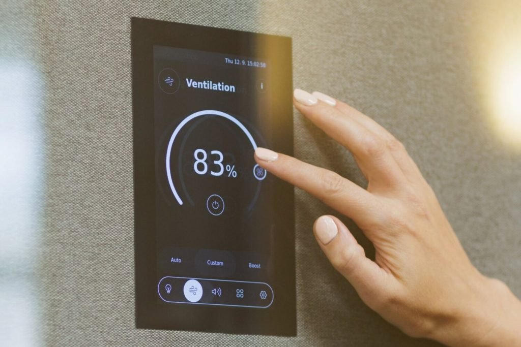 Una mano ajusta un panel de ventilación táctil que muestra una intensidad del 83 % en una cabina acústica de la colección GEN4