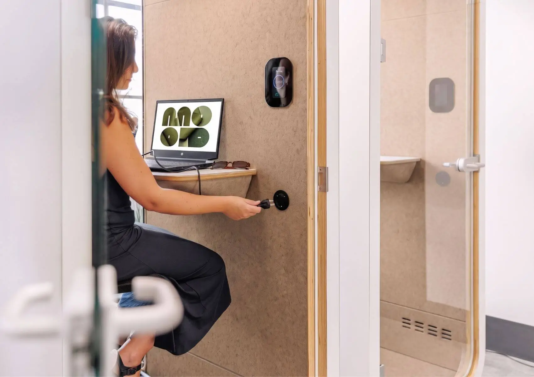 Una mujer utiliza un dispositivo portátil conectando un cabo de alimentación en un cabina acústica MOOD Phone