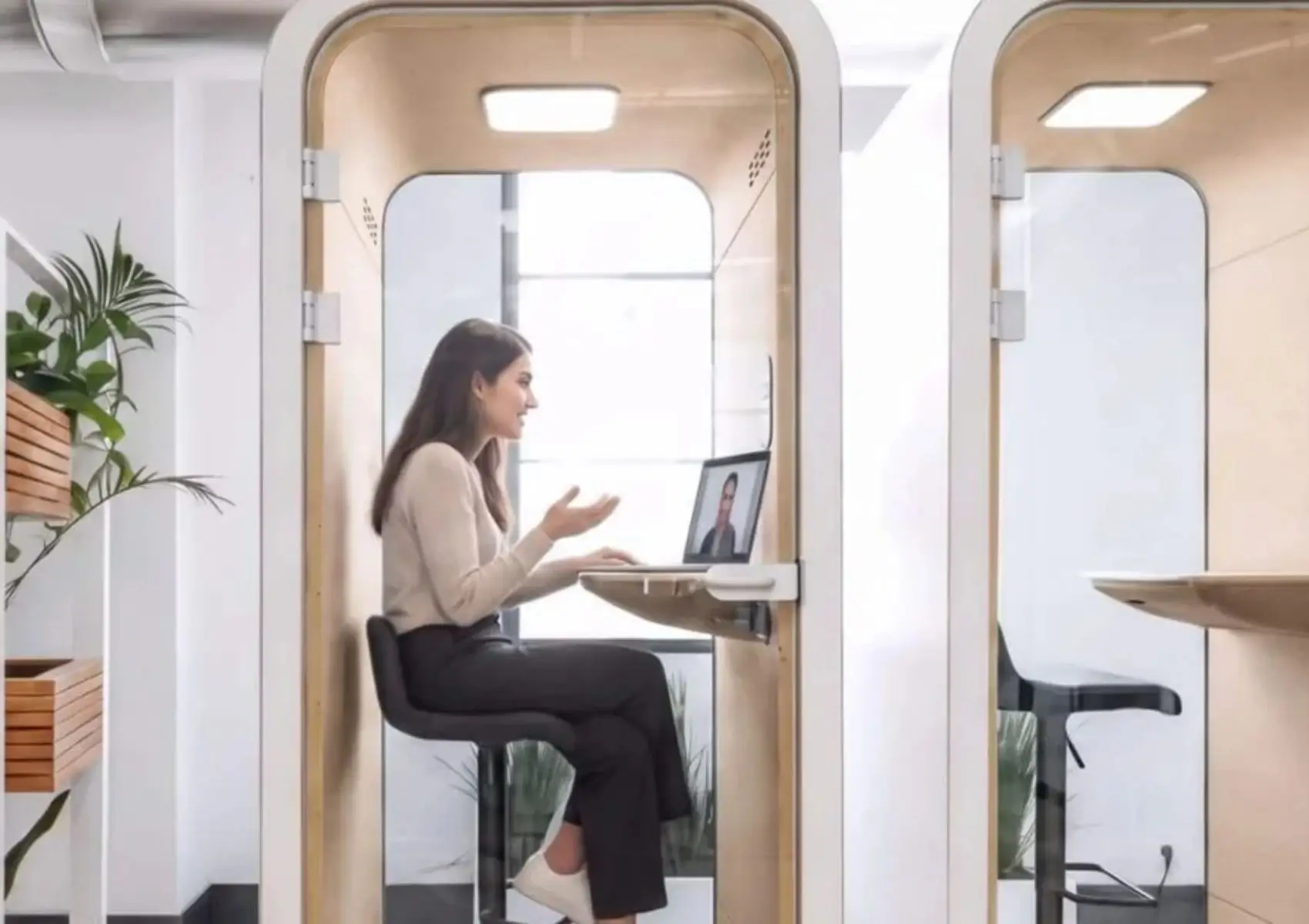 Una mujer sentada en una cabina acústica MOOD Phone realiza una videollamada desde un portátil